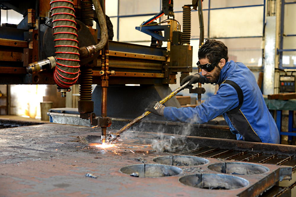 Un uomo lavora il metallo utilizzando una macchina.
