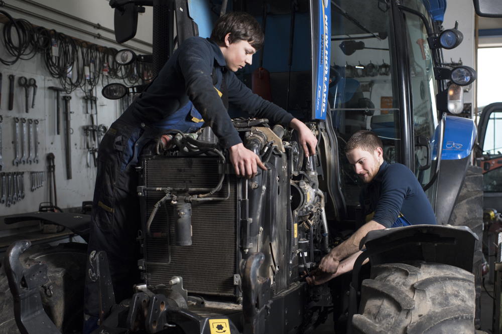 Un uomo e una donna riparano il motore di una macchina agricola o edile.