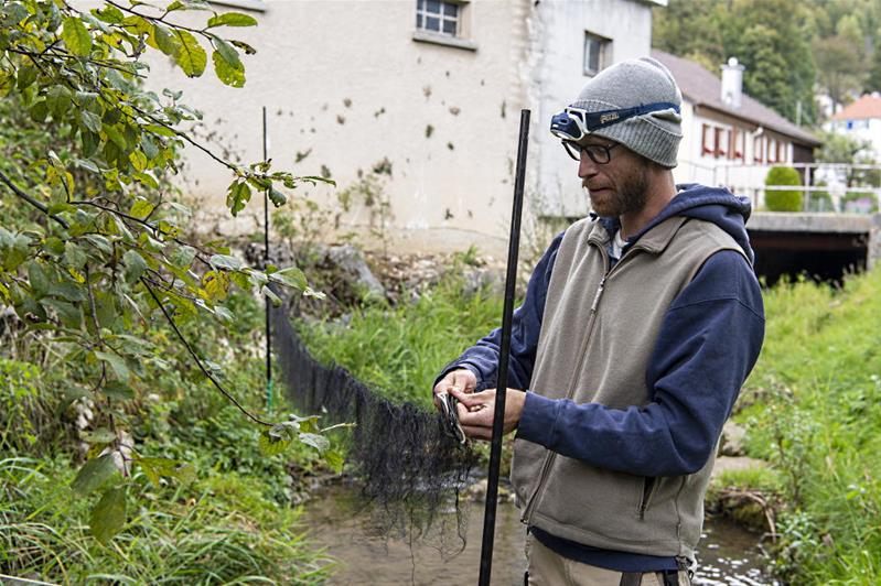 Un uomo prepara una rete sulla riva di un fiume.