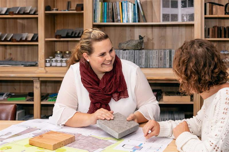 Una donna consiglia una cliente sulla scelta dei materiali per la ristrutturazione esterna