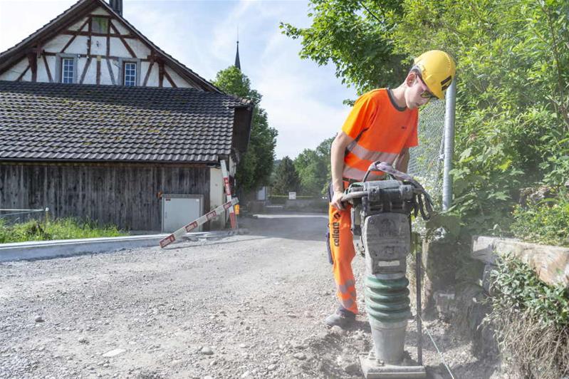 Un apprendista spiana la strada con un macchinario.