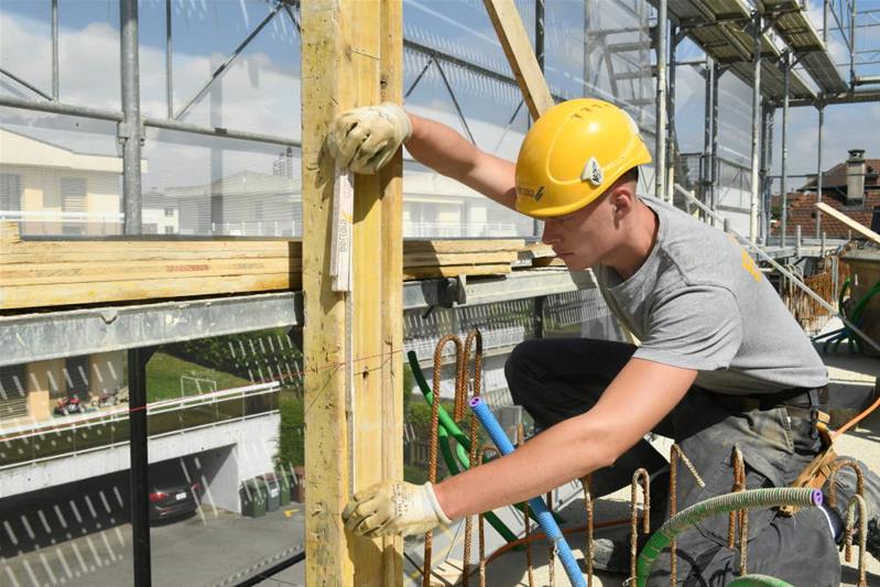 Un apprendista prende le misure per costruire un muro con i mattoni.