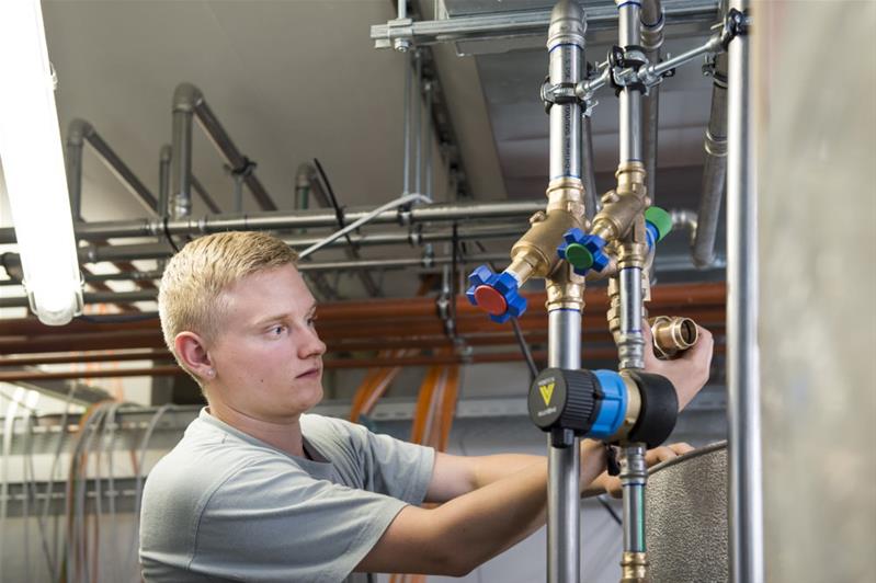 Un apprendista controlla le tubature dell’acqua.
