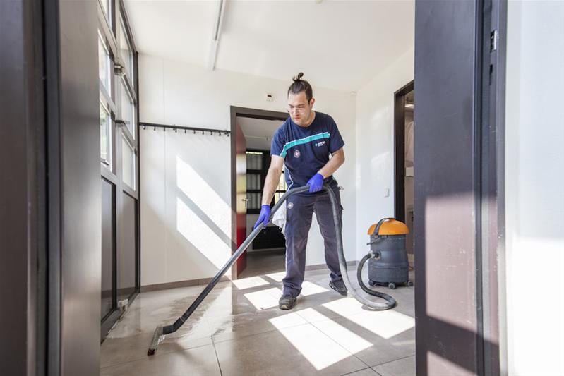 Un apprendista pulisce il pavimento con l'idropulitore.