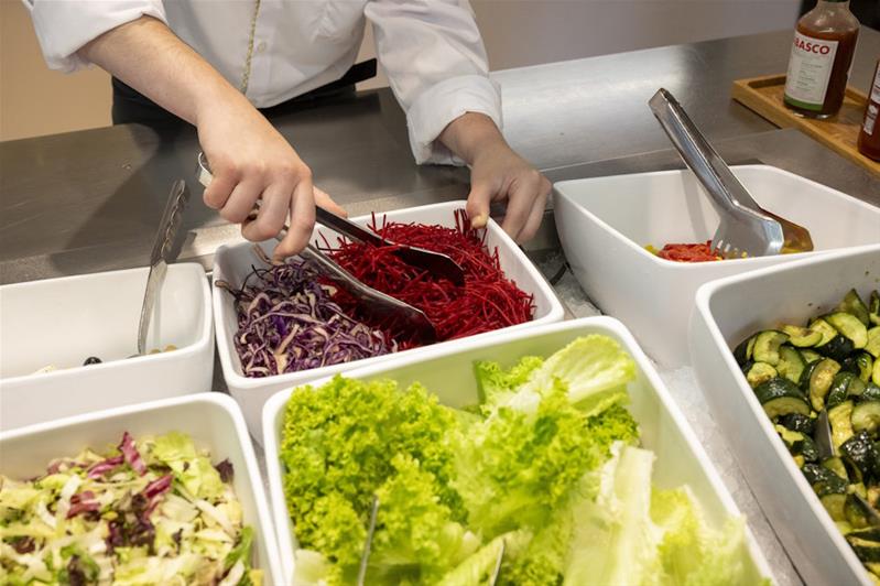 Un apprendista prepara il buffet delle insalate.