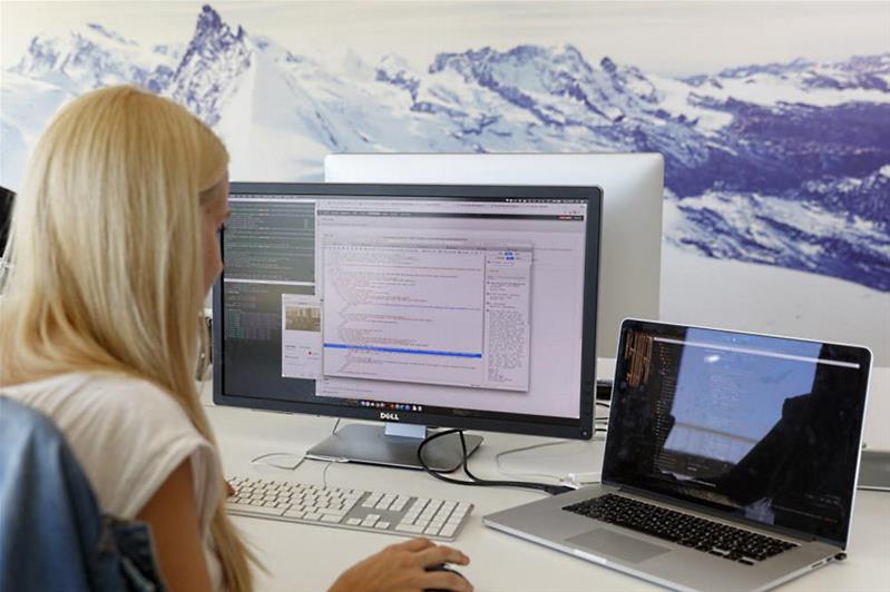 Una donna lavora davanti a due computer.
