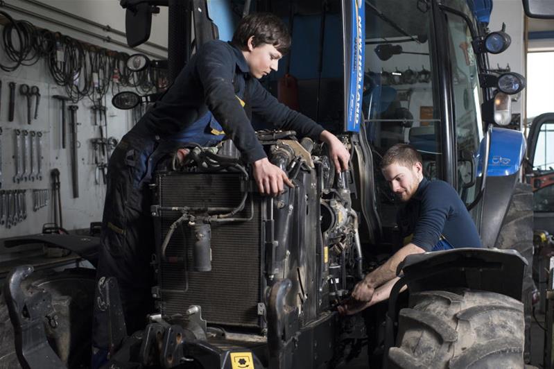 Un uomo e una donna riparano il motore di una macchina agricola o edile.