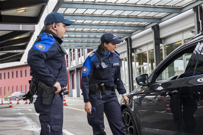 Un uomo e una donna lavorano per la dogana e per la sicurezza dei confini e fermano un veicolo in dogana.