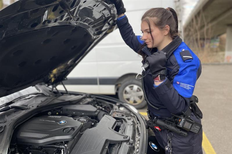 Una ragazza in uniforme controlla l'interno di un'automobile.
