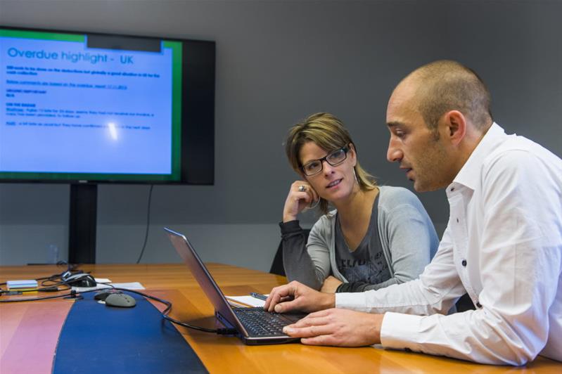 Un uomo e una donna discutono seduti a un tavolo davanti a un computer.