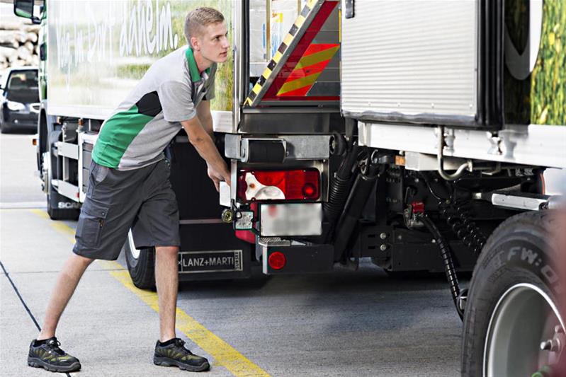 Un ragazzo è al lavoro in strada con il rimorchio di un camion.