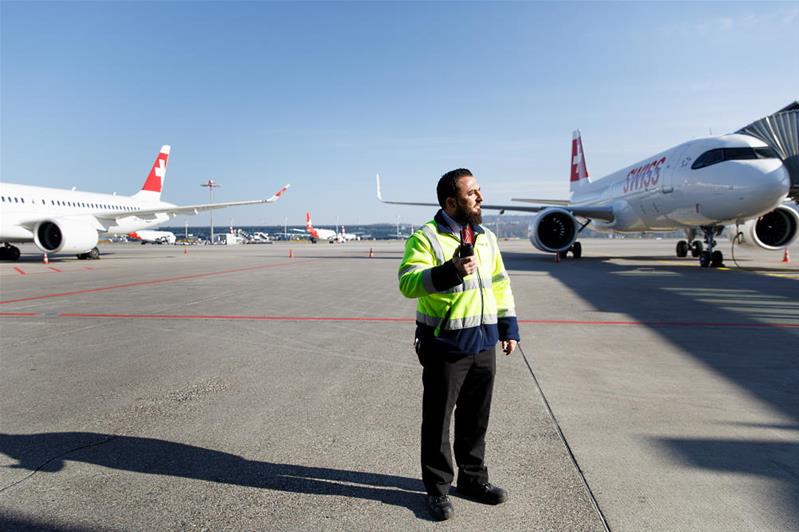 Un uomo che si trova tra due aeroplani è al lavoro all'esterno di un aeroporto.