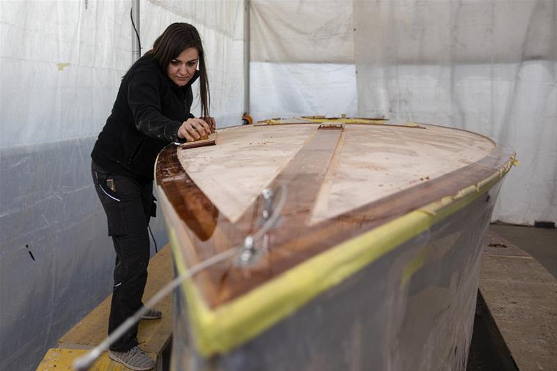 Una ragazza sta trattando il legno di una barca.