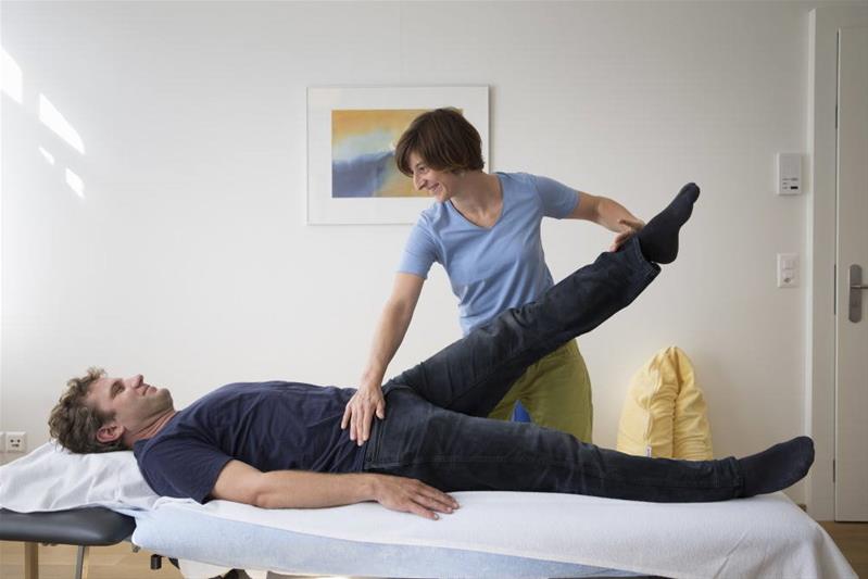 Una fisioterapista esegue dei trattamenti su un paziente che si trova sdraiato.