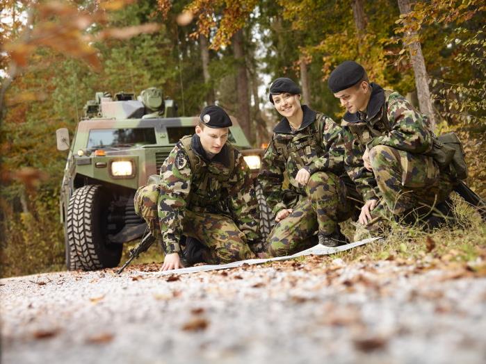 Tre membri dell'esercito svizzero studiano una mappa.
