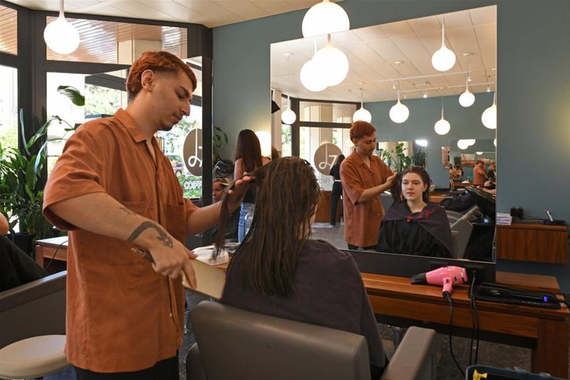 Un apprendista spazzola i capelli di una cliente.
