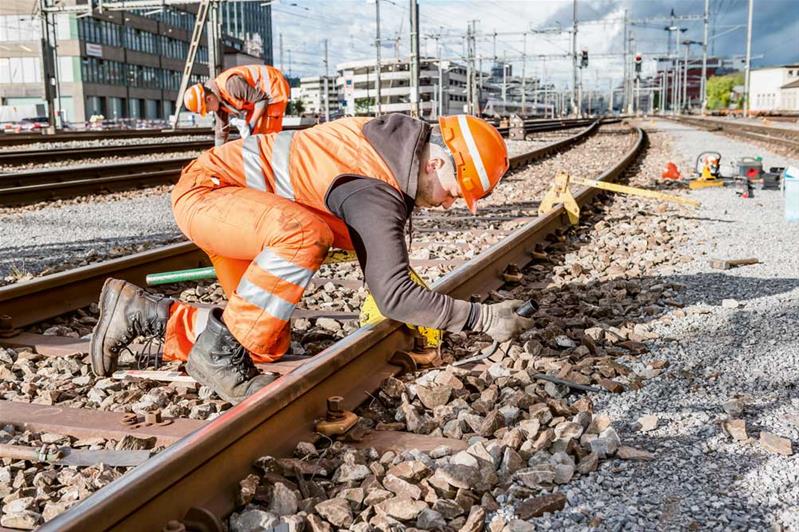 Un apprendista lavora all’aperto e controlla un binario.