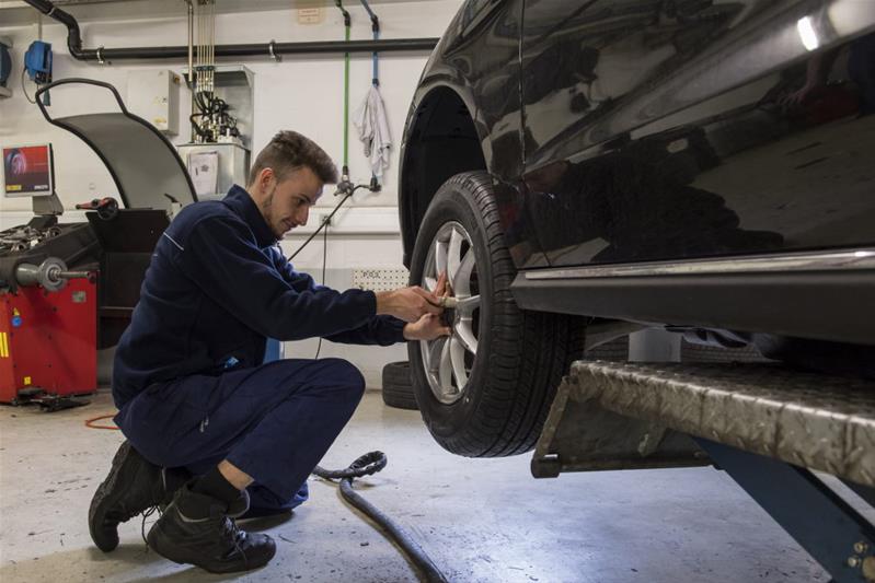 Un apprendista controlla la ruota di un’automobile.